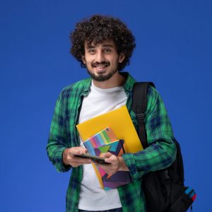 front-view-male-student-wearing-black-backpack-holding-copybook-files-using-his-phone-light-blue-wall front-view-male-student-wearing-black-backpack-holding-copybook-files-using-his-phone-light-blue-wall