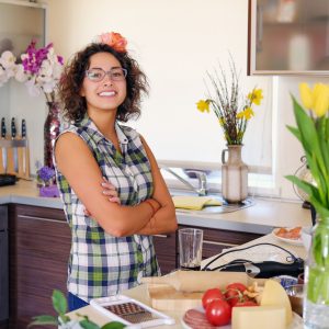 Brunette attractive female with curly hair in a home kitchen with a lot of flowers. Portrait of brunette attractive female with curly hair in a home kitchen with a lot of flowers.
