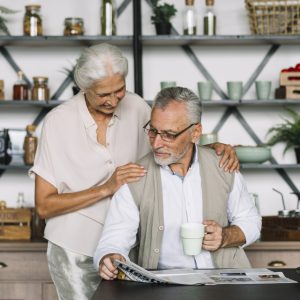woman-standing-her-husband-reading-newspaper woman-standing-her-husband-reading-newspaper
